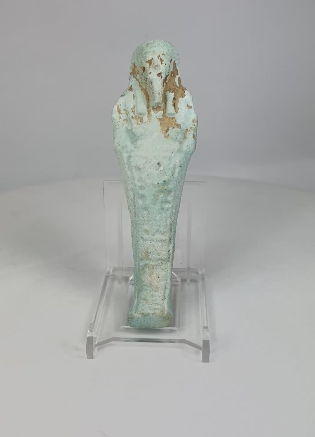360° video of an ancient Egyptian turquoise-blue faience Ushabti rotating on a clear stand against a white background