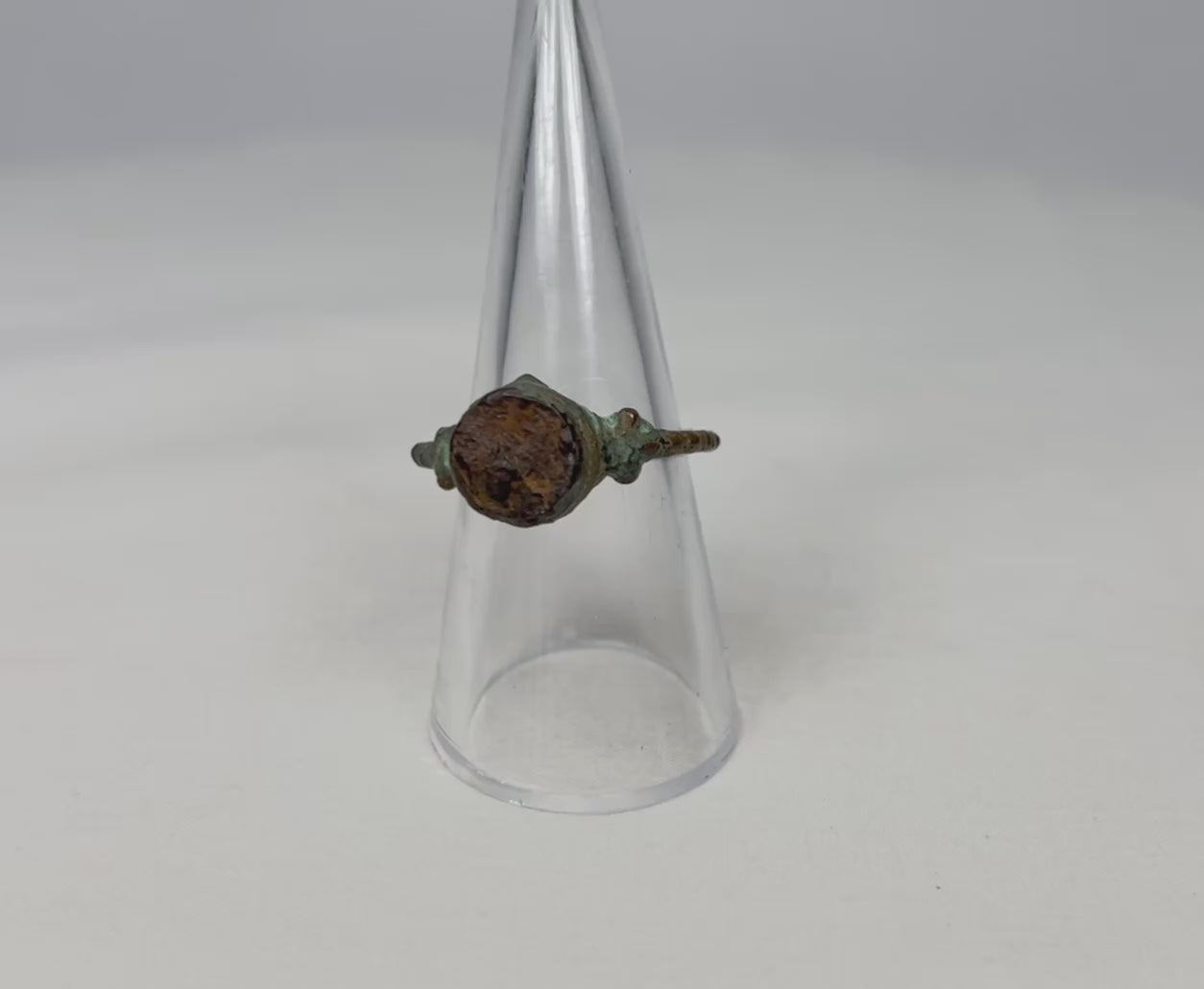 360-degree video of an ancient bronze ring rotating on a clear display cone