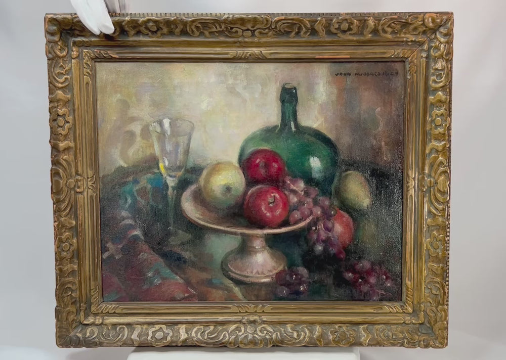 Early 20th-century American oil on canvas still life by John Hubbard Rich, depicting apples, grapes, a wine bottle, and goblet in a giltwood frame, photographed against a white background.