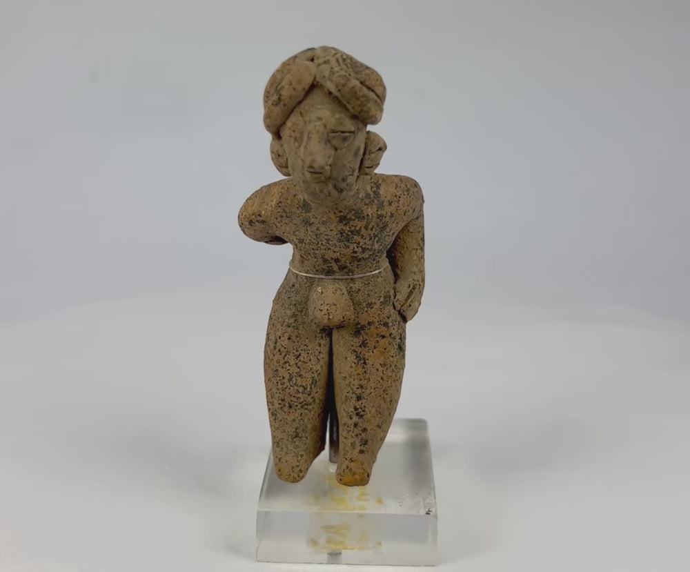 Slow rotating video of a Pre-Columbian West Mexican terracotta shaft-tomb figure with turban-style headdress, showing surface texture, burial encrustations, and mounted acrylic base from multiple angles