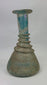 360-degree view of an ancient Roman turquoise glass unguentarium showing spiral trailing, elegant neck, flared rim, and mineral patina from centuries of burial