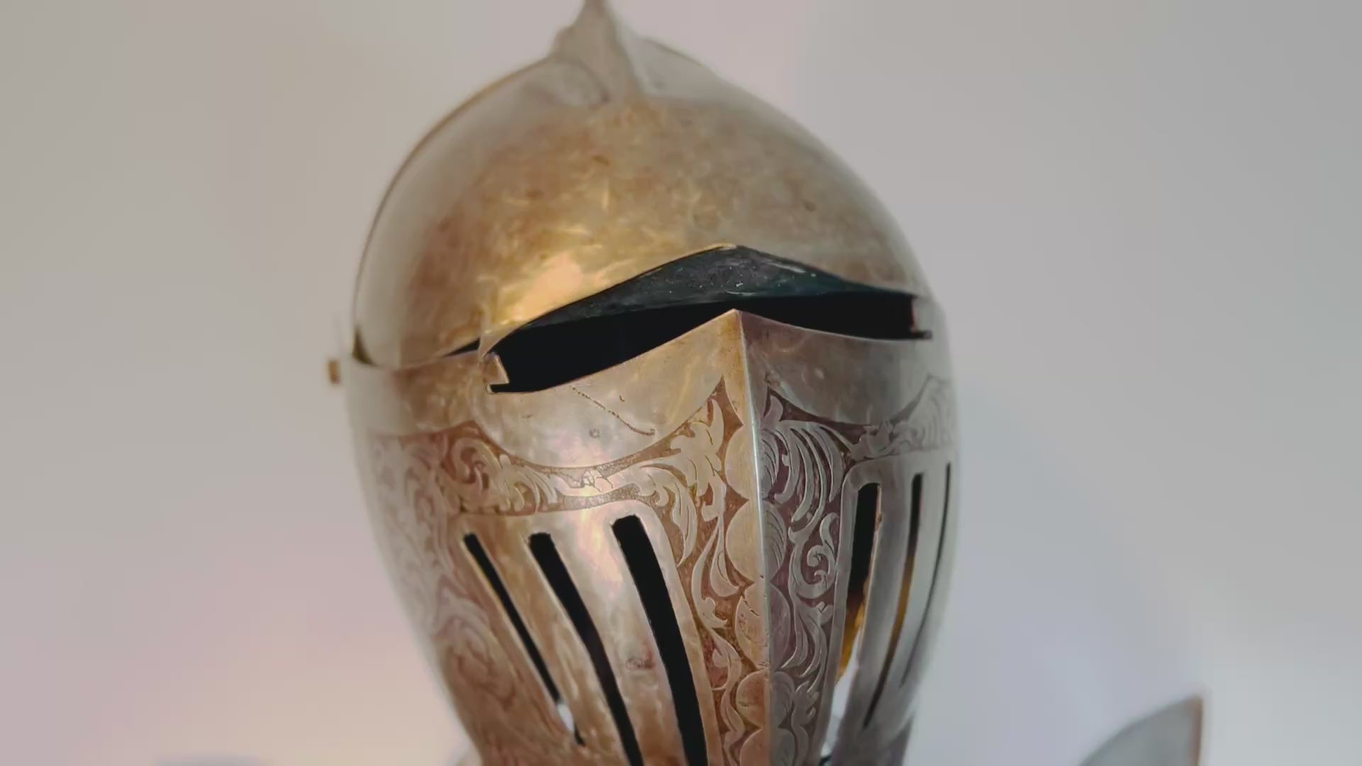 Victorian-era full suit of armor, early 19th century, 80 inches tall by 32 inches wide. Acid-etched metal plates decorated with intricate engravings of mythical creatures, dragons, crowns, battle scenes, and scrolling foliage. Inspired by 15th-century medieval armor, reflecting Victorian fascination with chivalric ideals and Gothic artistry. Mounted on a custom wooden display stand.