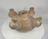 Rotating presentation of an ancient Colima five-spout ceramic vessel with a central chamber, four surrounding openings, burnished brown slip, and archaeological surface deposits.