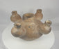Rotating presentation of an ancient Colima five-spout ceramic vessel with a central chamber, four surrounding openings, burnished brown slip, and archaeological surface deposits.