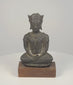Video of a crowned bronze Buddha seated in meditation, with winged ear ornaments, dark patina, and a wooden display base.