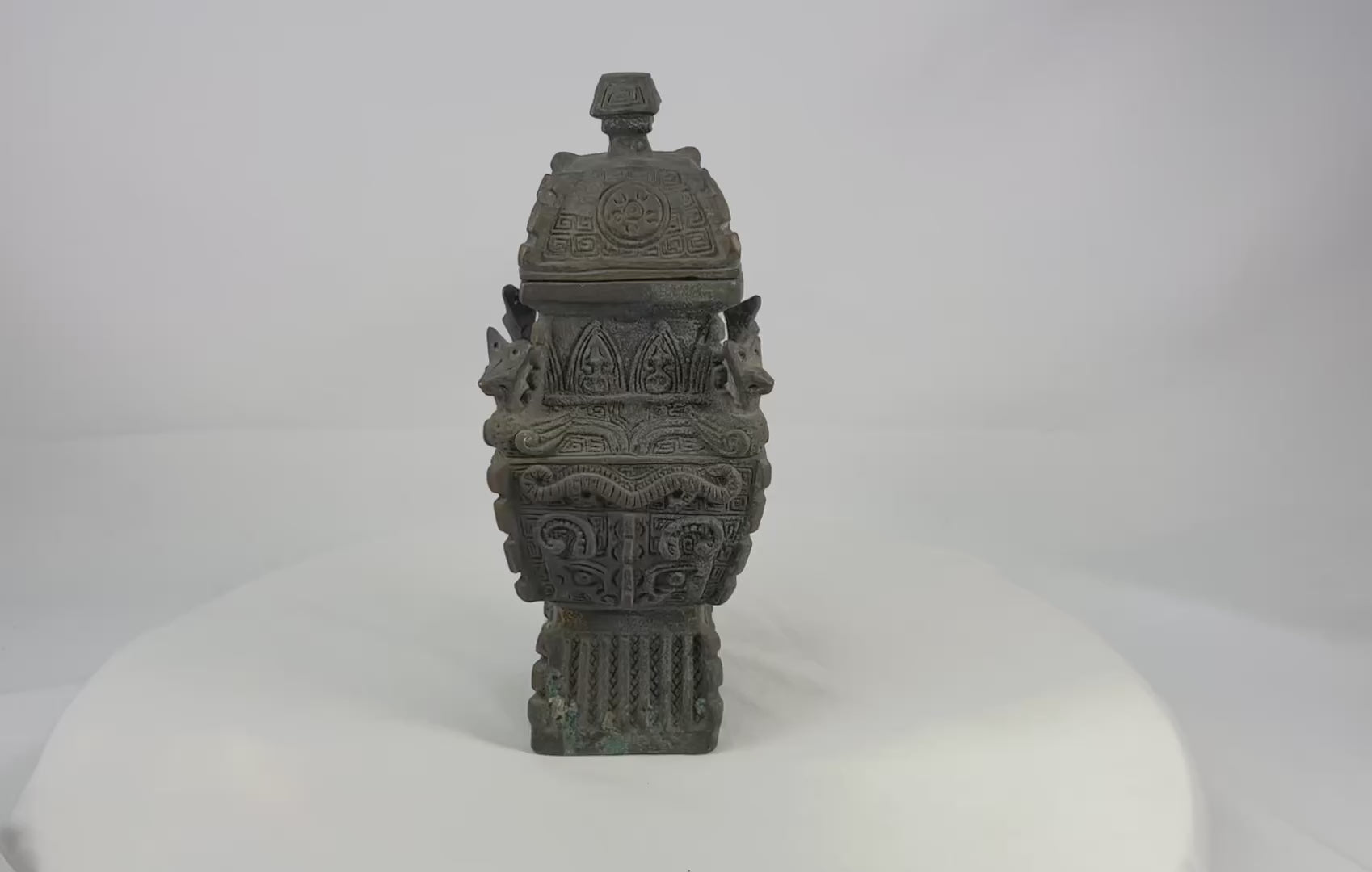 Square Chinese fang yi bronze vessel with roofed lid, cast taotie masks, leiwen ground, curled kui dragons, and zoomorphic shoulder protomes, dark patina with green/blue encrustation, late Qing to early Republic period, ca. 1880–1930.