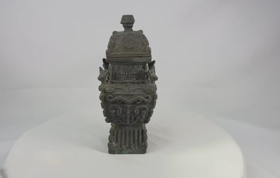 Square Chinese fang yi bronze vessel with roofed lid, cast taotie masks, leiwen ground, curled kui dragons, and zoomorphic shoulder protomes, dark patina with green/blue encrustation, late Qing to early Republic period, ca. 1880–1930.