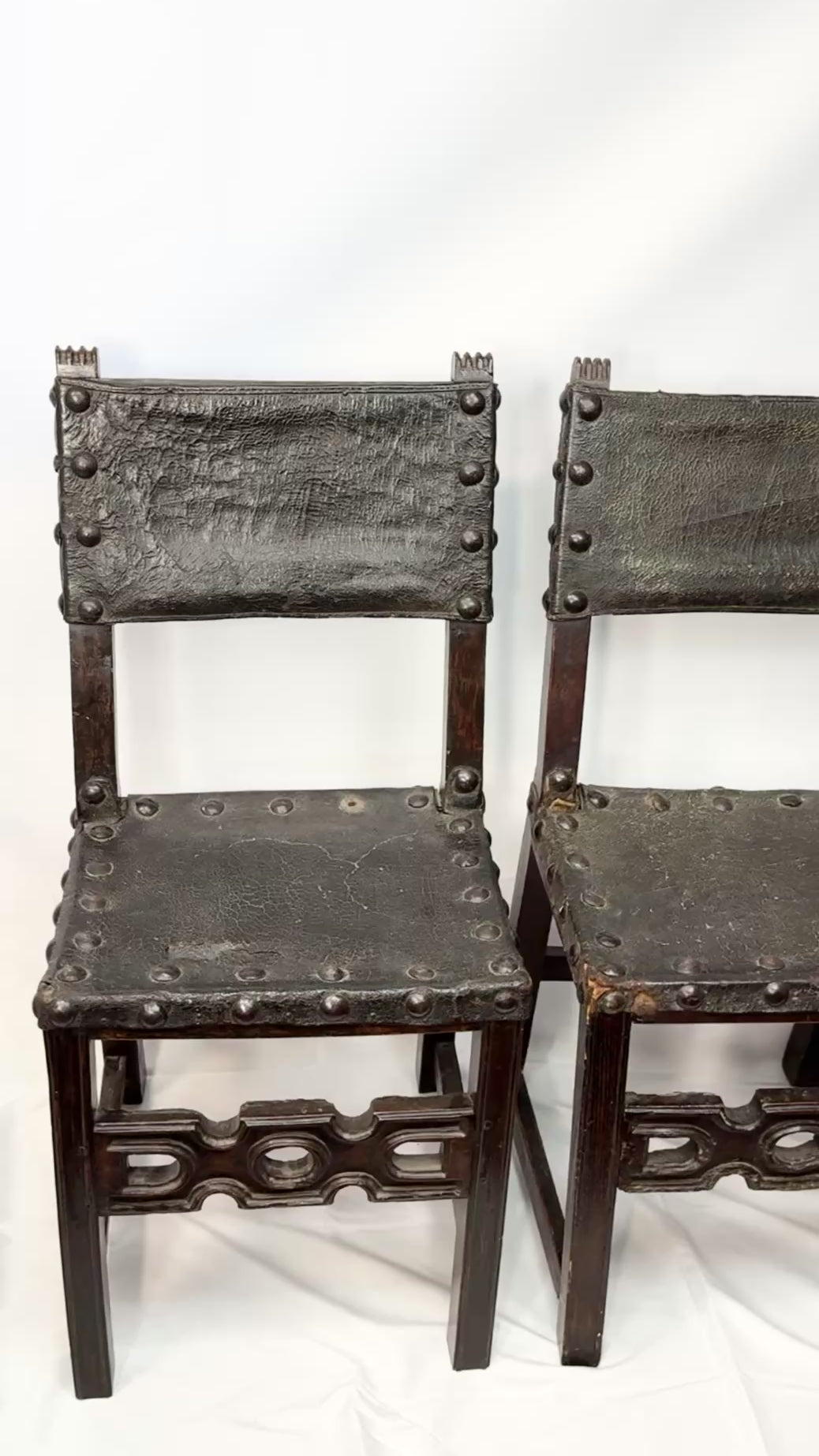 Close-up video zooming in on a pair of 17th-century Spanish Baroque walnut chairs with studded leather upholstery.