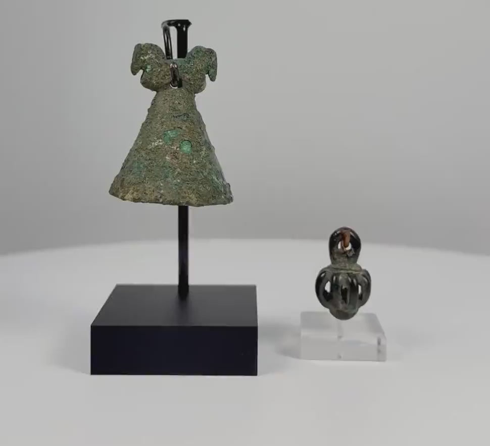 360-degree rotating view of two ancient Iranian bronze pendant bells, including a Luristan Iron Age example dating to the 10th–7th century BCE. Features distinctive openwork bronze construction, suspension loops, decorative metalwork, and naturally aged green patina, showcasing ancient Persian craftsmanship and historical bell-making traditions.