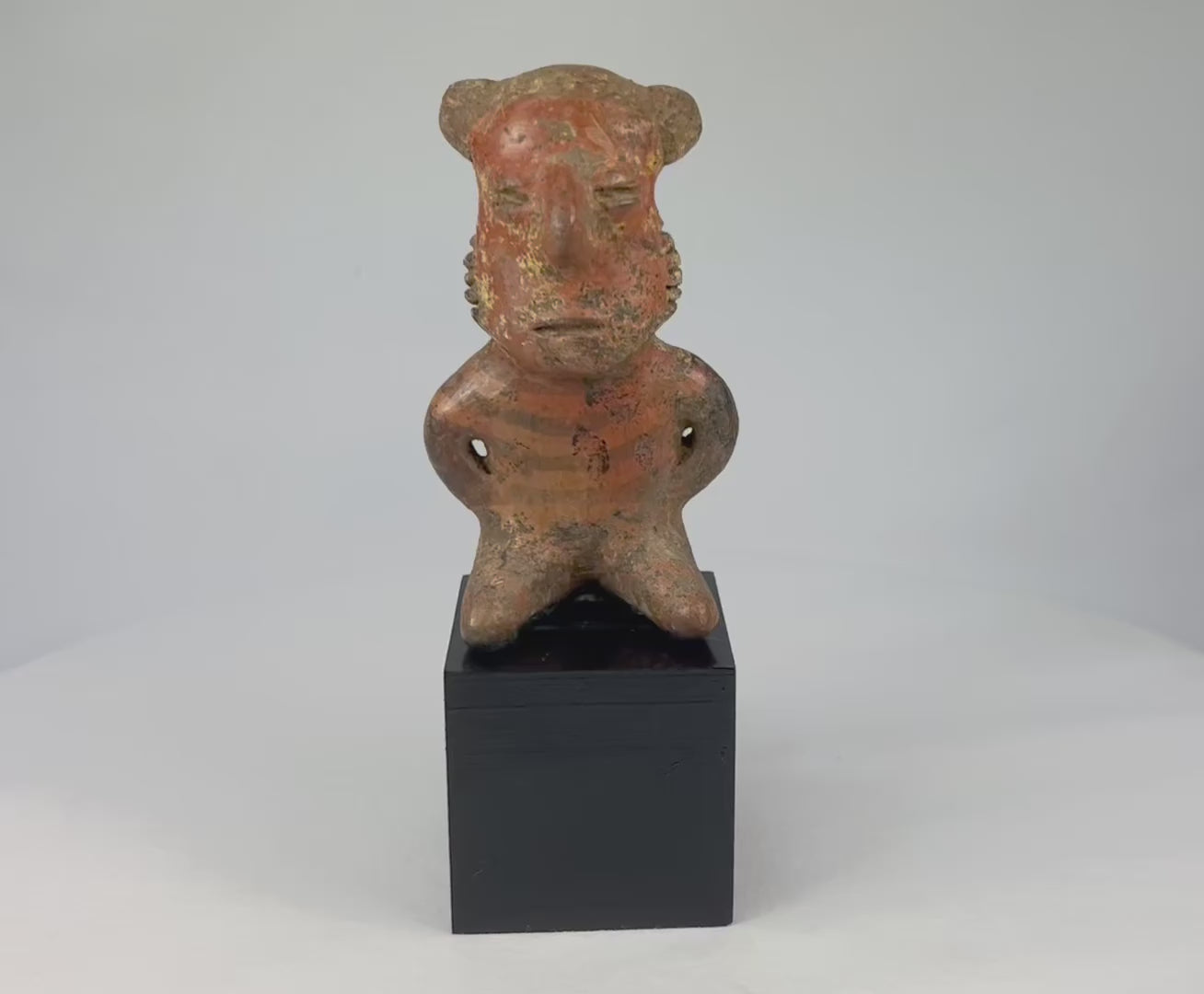 Pre-Columbian West Mexican terracotta figure, circa 300 BCE–500 CE, hand-modeled with stylized features and faint red-orange pigment, Nayarit, Colima, or Jalisco shaft tomb culture, mounted on display base