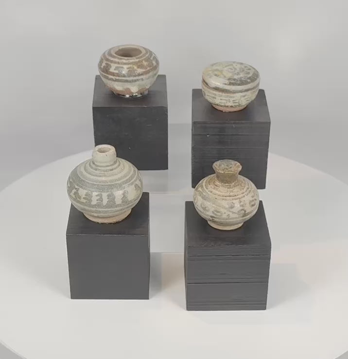 Rotating view of four authentic Sawankhalok glazed stoneware vessels from the Sukhothai Period of Thailand, highlighting their miniature forms, underglaze iron-black decoration, transparent glaze, custom display stands, and centuries-old ceramic craftsmanship.