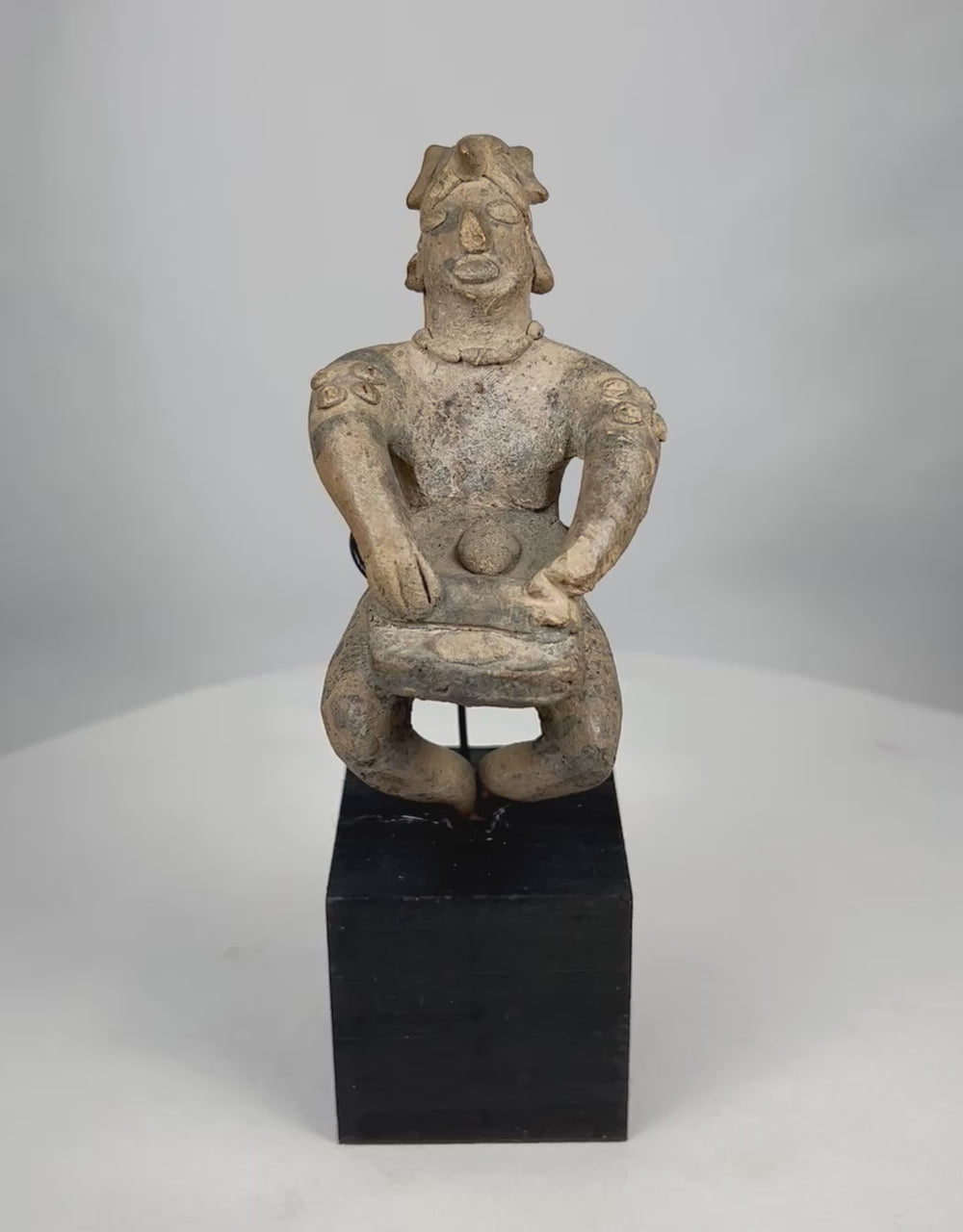 Ancient West Mexican Pre-Columbian terracotta musician figure rotating on stand, showing full sculptural form, nodular shoulder decorations, burial patina, and expressive seated posture.