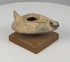 360-degree rotating view of an ancient Byzantine terracotta oil lamp dating to the 5th–7th century CE, featuring a slipper-shaped body, raised central filling hole, elongated wick nozzle with darkened residue, conical rear handle, and molded geometric chevron decorations. The weathered earthenware surface displays natural patina, age-related wear, and pale encrustations. Presented on a rectangular wooden display base.