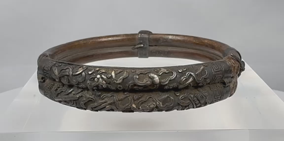 Rotating view of an antique Qing Dynasty Chinese bracelet constructed from parallel bamboo sections with applied silver-alloy floral decoration, metal collars, original bindings, and an aged patina