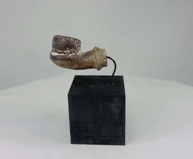 Slow rotating video of an 18th–19th century Middle Eastern earthenware pottery fragment showing rounded chamber, projecting stem, mineral deposits, and surface patina from multiple angles