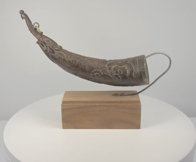 Rotating 360-degree view of an antique Tibetan carved ritual horn, showing its curved form, makara tip, decorative carvings, and aged patina.