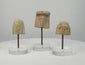 360° rotating video showcasing a set of three ancient Greek terracotta female protomai bust plaques, dating to the 6th–4th century BCE. Each fragment features distinct facial details, hairstyles, and headdresses, with natural patina and age-related wear. Individually mounted on clear acrylic display stands.