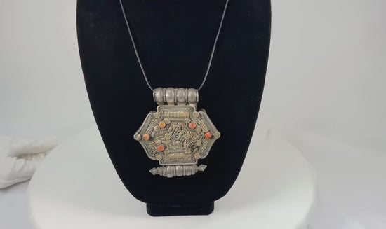 Hexagonal Himalayan gau (ghau) amulet pendant in silver-tone alloy with parcel-gilt filigree, rosette appliqués, inset coral beads, and small turquoise cabochon, featuring hollow reliquary cavity and tubular suspension bales, late 19th–early 20th century, Tibet/Nepal