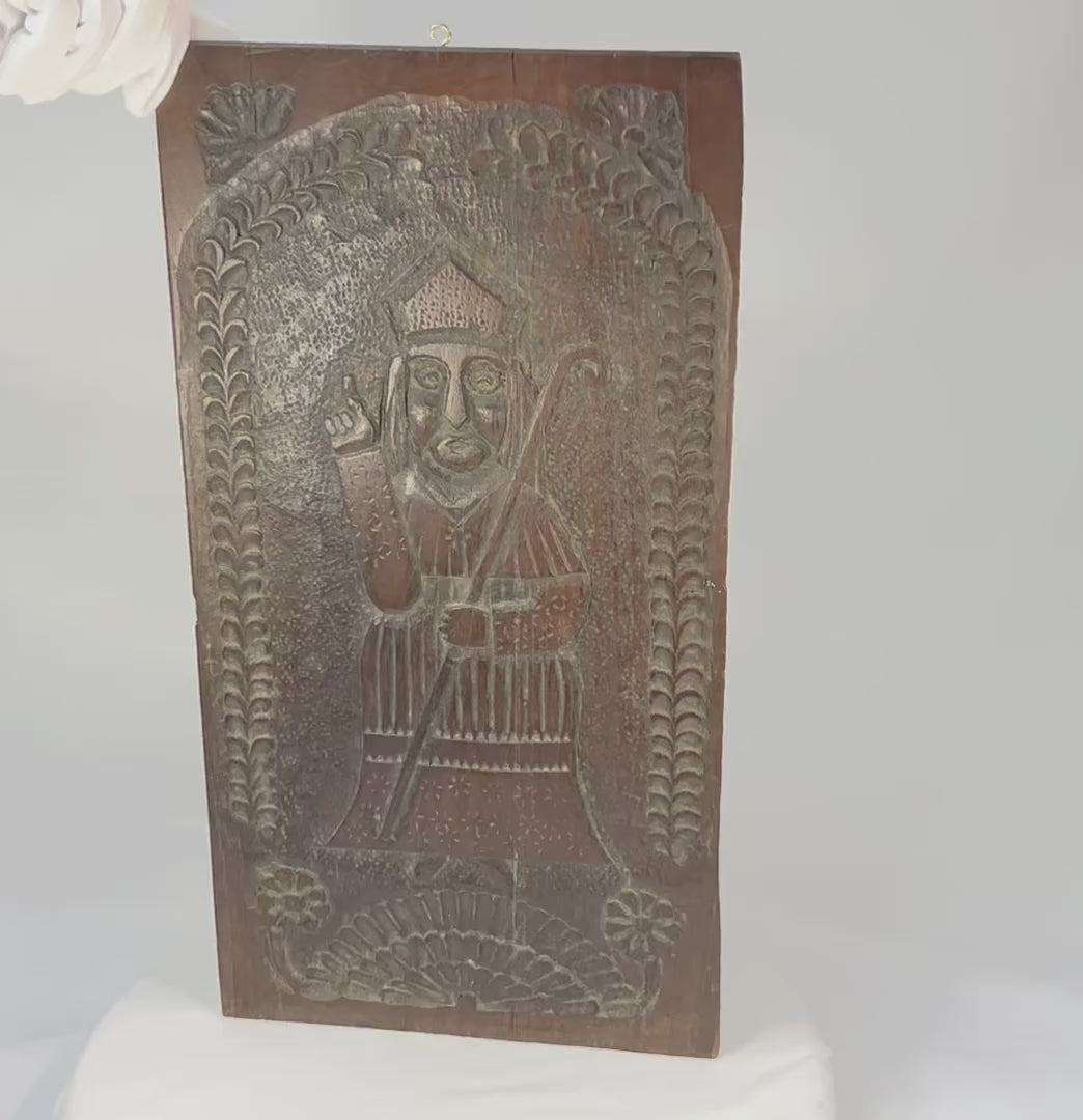 Hand-carved hardwood devotional panel depicting a bishop saint, likely St. Nicholas, with crozier and blessing gesture, foliate border with rosettes, Central/Eastern Europe, c. 1780–1830, 18 7/8 x 9 3/4 inches