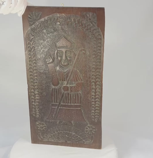Hand-carved hardwood devotional panel depicting a bishop saint, likely St. Nicholas, with crozier and blessing gesture, foliate border with rosettes, Central/Eastern Europe, c. 1780–1830, 18 7/8 x 9 3/4 inches