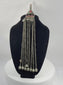 Antique Afghan Kuchi tribal pendant featuring a cylindrical hirz prayer tube, red glass cabochons, silver-toned metalwork, cascading chain tassels, and bell-shaped pendants, showcasing traditional nomadic ceremonial craftsmanship from the late 19th to early 20th century.