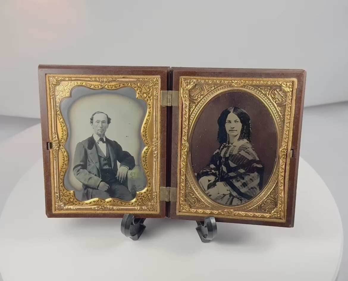Rotating view of a mid-19th-century double ambrotype set with portraits of a Victorian gentleman and young woman, gilt brass mats, velvet lining, and an ornate molded thermoplastic union case