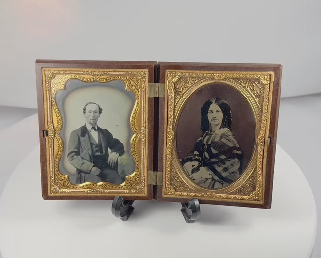 Rotating view of a mid-19th-century double ambrotype set with portraits of a Victorian gentleman and young woman, gilt brass mats, velvet lining, and an ornate molded thermoplastic union case