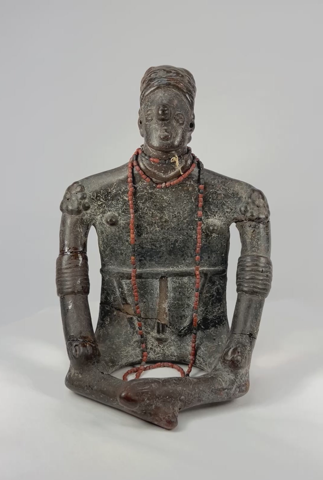 360° rotation of ancient terracotta shaman figure showing red beaded necklaces and detailed surface patina.