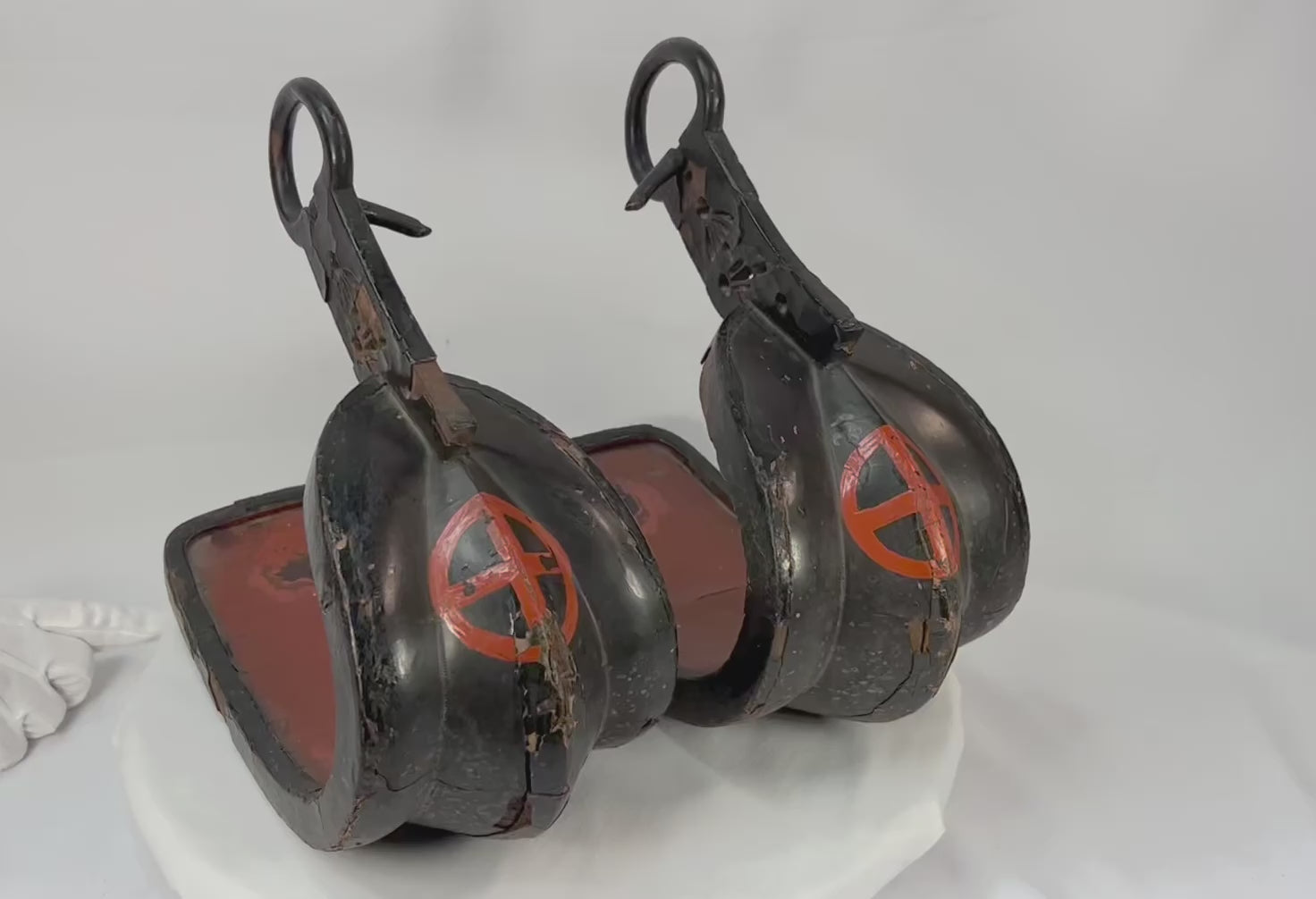 Matched pair of Edo–Meiji Japanese abumi (samurai stirrups) with black lacquer exterior, red interior, and Shimazu (Satsuma) clan cross-in-circle crest, featuring forged iron hangers and deep curved footbeds, circa 1800–1880.