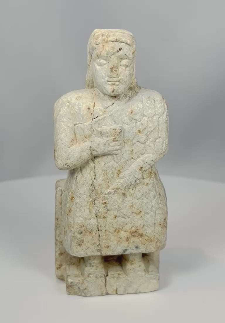 Rotating view of ancient Mesopotamian carved stone worshipper figurine with clasped hands and aged patina