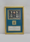 Video of a framed ancient Egyptian-style blue-green glazed scarab amulet, attributed to circa 2345–30 BCE, mounted within a gold-toned display against a deep blue background. The gilt frame features Egyptian-inspired artwork depicting a sacred scarab, solar disk, and winged figures, with an accompanying historical identification plaque.