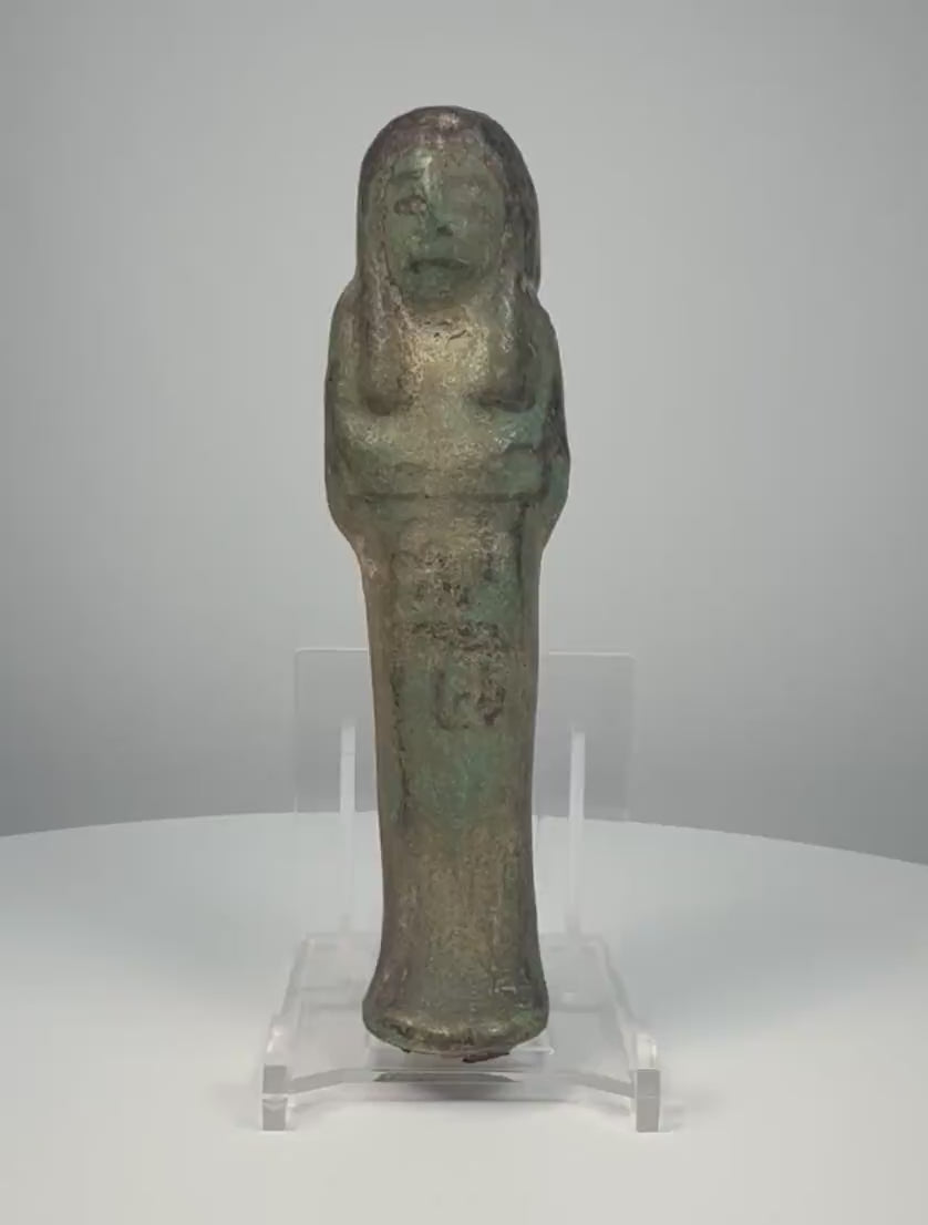 Ancient Egyptian blue-green glazed faience ushabti from the Third Intermediate Period, 21st–22nd Dynasties, circa 1070–715 BCE, featuring crossed arms, a tripartite wig, surviving black-painted hieroglyphic inscriptions, and aged turquoise glaze. Formerly in the Dr. Bruce L. Ralston Collection.