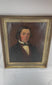 Video view of an early Victorian British oil portrait depicting an unidentified gentleman with dark arranged hair, prominent sideburns, a dark frock coat, burgundy waistcoat, cream shirt, high collar, and patterned silk cravat, shown in an antique giltwood frame with visible craquelure, surface wear, aged varnish, and the original canvas and wooden stretcher on the reverse