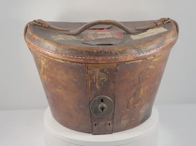 360-degree rotating view of an antique British Scott &amp; Co. black silk top hat and original fitted brown leather travelling case, circa 1930s–1940s. Features original Cunard White Star RMS Queen Mary passenger luggage label identifying Mr. James Hargreaves, historic LNER King's Cross railway label, aged leather construction, and period metal fittings.