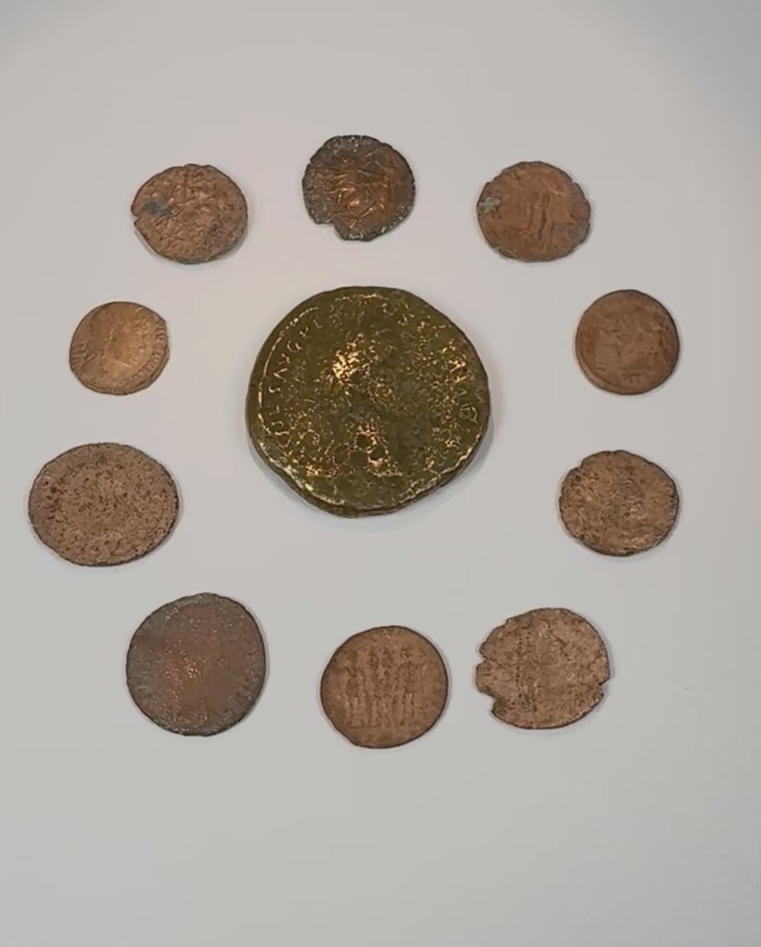 Video overview of a collection of 10 ancient Roman bronze coins, showing the large central imperial coin, smaller Late Roman issues, portraits, reverse designs, and varied archaeological patina.