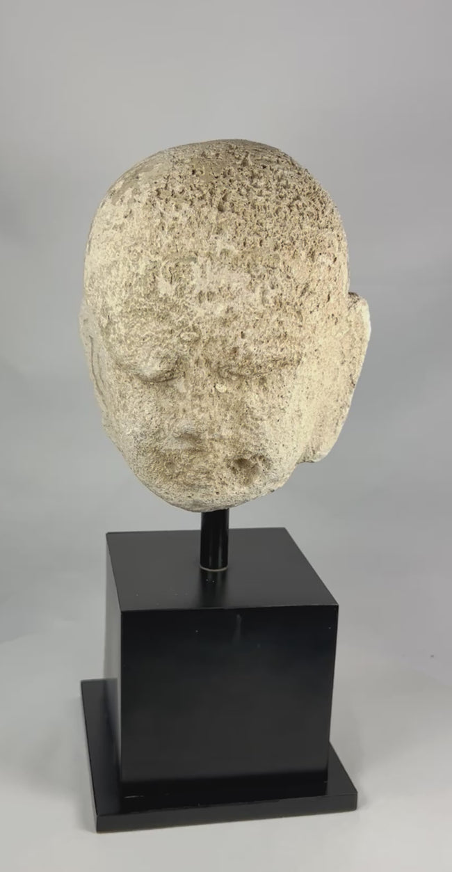 Southeast Asian carved stone Buddha head with serene expression and closed eyes, 13th–14th century, mounted on a modern black stand, Burma or Thailand.