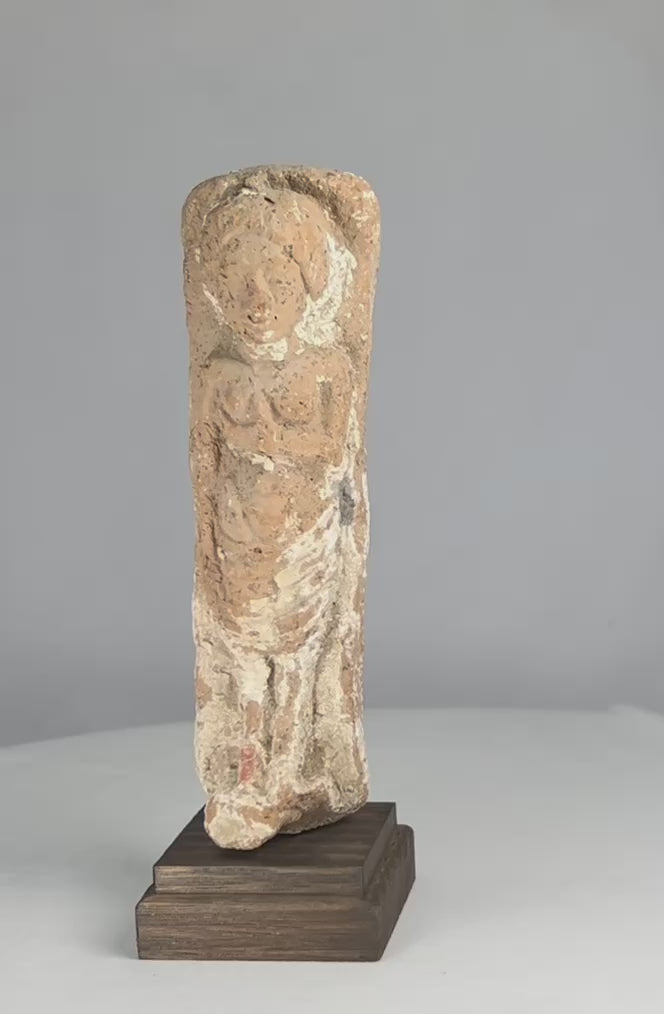 Iron Age terracotta fertility goddess figurine from the Levant, circa 600–300 BCE, stylized female form with one arm raised to the breast; faint red and white pigment traces visible on the surface, symbolizing abundance and protection.
