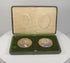 360-degree rotating view of a matched pair of late Victorian to Edwardian colour portrait miniatures, circa 1880–1910 CE, depicting a formally dressed gentleman in a dark suit and a woman in a blue gown with a white lace collar. Both portraits feature gilt-coloured oval surrounds set within a deep green velvet presentation panel, accompanied by a fitted green leather-covered case with cream satin lining and folding easel support. Formerly part of the historic Sears family collection from the estate of Josep