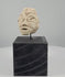 Video showcasing a Mesopotamian-style carved stone head fragment, highlighting its almond-shaped eyes, broad nose, simplified mouth, weathered limestone surface, and modern black display stand.