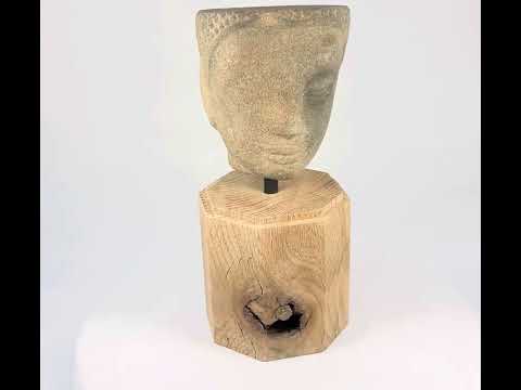 Khmer sandstone head fragment from the Angkor Period, 12th century Cambodia, depicting a serene deity or Buddha with downcast eyes and soft expression, mounted on a wooden display base, photographed on a white background.