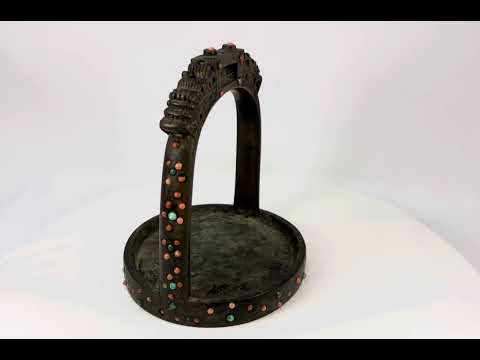 Ornate cast bronze stirrup from Mongolia or Himalayan region, featuring dragon-head terminals, pierced latticework, and hand-set coral, turquoise, and glass inlays, 7 inches tall by 6 inches wide, with natural patina and verdigris, circa 18th century.