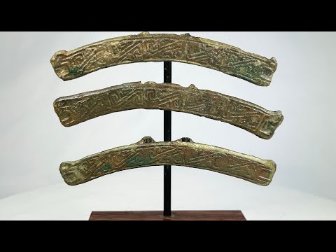 Ancient Chinese bronze chariot fittings, 475 BCE–220 CE, with curved form, rear hooks, engraved inscriptions, and rich green patina on custom stands.