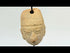 Terracotta pendant head with angular headdress, incised almond-shaped eyes, furrowed brow, and pronounced nose and lips; drilled suspension hole through top; mounted on a museum-style stand; West Mexico (Colima/Nayarit) or Veracruz, circa 300 BCE–300 CE.