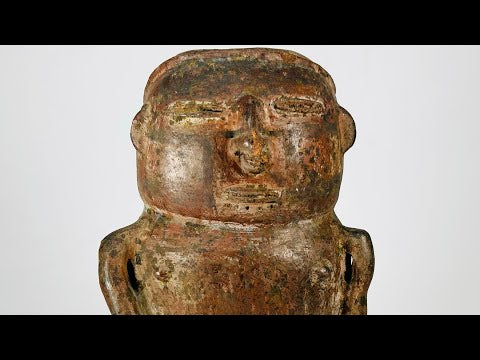 A Pre-Columbian terracotta effigy vessel depicting a seated human figure with stylized facial features, hands on lap, and an opening at the top of the head for offerings, dating to circa 500 BCE–900 CE.