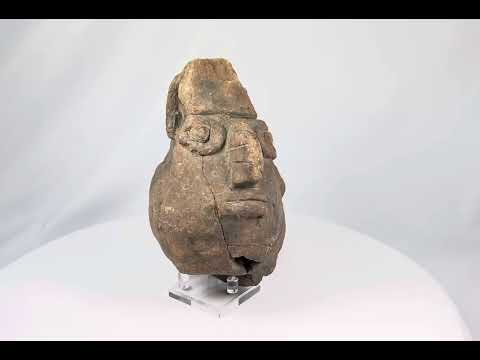 Pre-Columbian anthropomorphic spouted jar from the Valdivia–Chorrera culture, Ecuador, shaped as a stylized human head with large circular eyes, broad nose, and pronounced lips; hand-molded terracotta with earthy patina, ritual vessel dating to early Andean traditions, showing surface wear and archaeological age cracks.