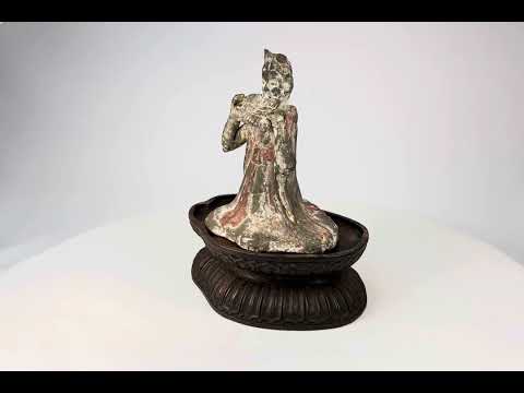 Tang Dynasty terracotta figure of a seated female court musician playing a pan flute, traces of red and white pigments, displayed on a carved wooden stand, 7th–9th century China.