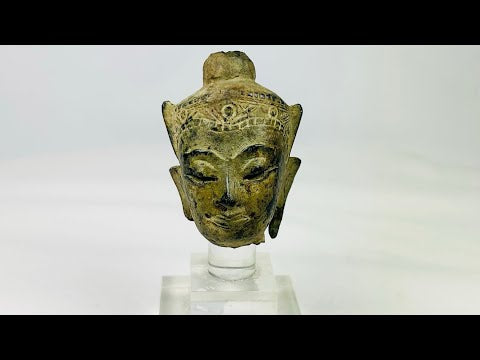 Fragmentary cast bronze Buddha head with serene expression, arched brows, closed eyes, subtle smile, and engraved crown band; traces of gilt and lacquer; likely Thailand or Burma, Late Ayutthaya–Early Rattanakosin or Toungoo–Konbaung period, circa 15th–18th century CE; mounted on a custom acrylic stand.