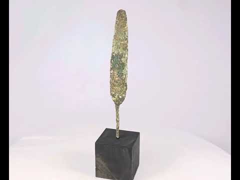 Ancient bronze spearhead from the Early to Late Bronze Age (circa 3300–1200 BCE). Leaf-shaped blade with tapered point, mounted on a modern display base. Exhibits natural patina and surface oxidation, reflecting early metallurgical craftsmanship and use in hunting or combat.