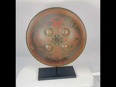 Small circular Indo-Persian Dhal shield, 11 inches diameter, lacquered black and red with damascened foliate motifs, four raised bosses, interior grips with knuckle-guard cushion, well-preserved antique.