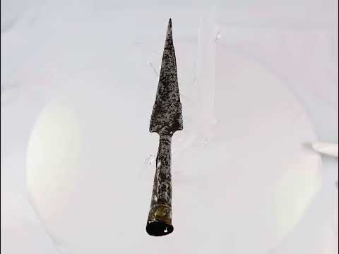 Video showing a 360 view of a hand-forged European iron spear head from the 16th–17th century rotating on display for inspection.